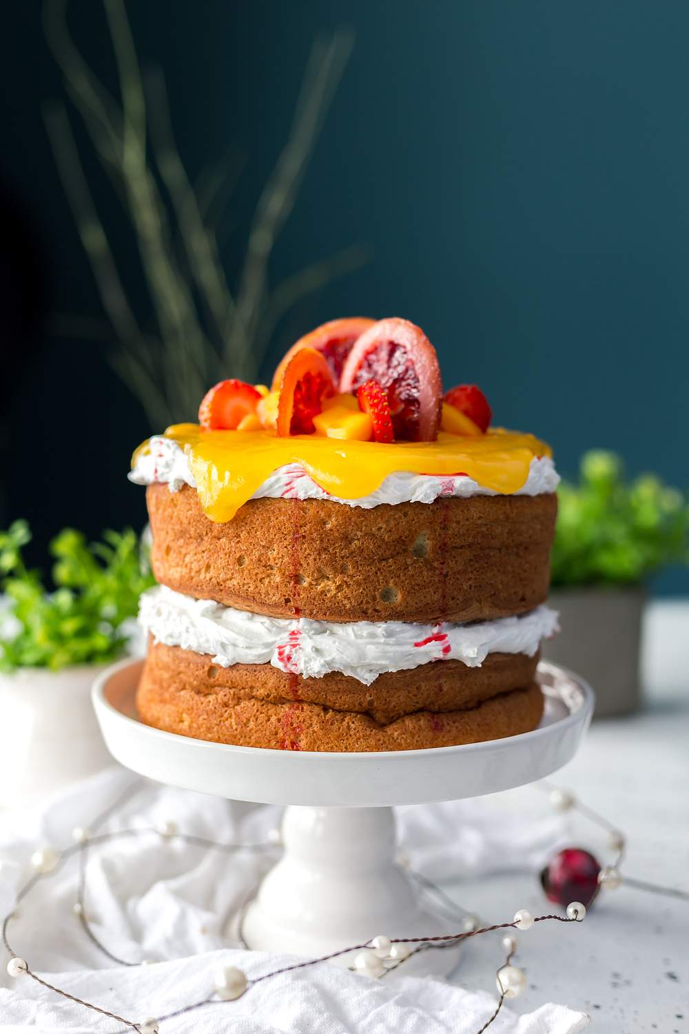 A layered afternoon tea cake topped with fresh fruit